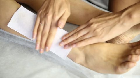 Women legs and hair removal with hot wax painful procedure. Woman In A Beauty Salon Doing Depilation. Wax depilation in a beauty salon