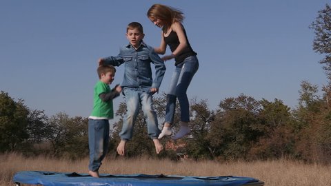 Slow motion of teenage girl and cute young boys having fun jumping on a trampoline