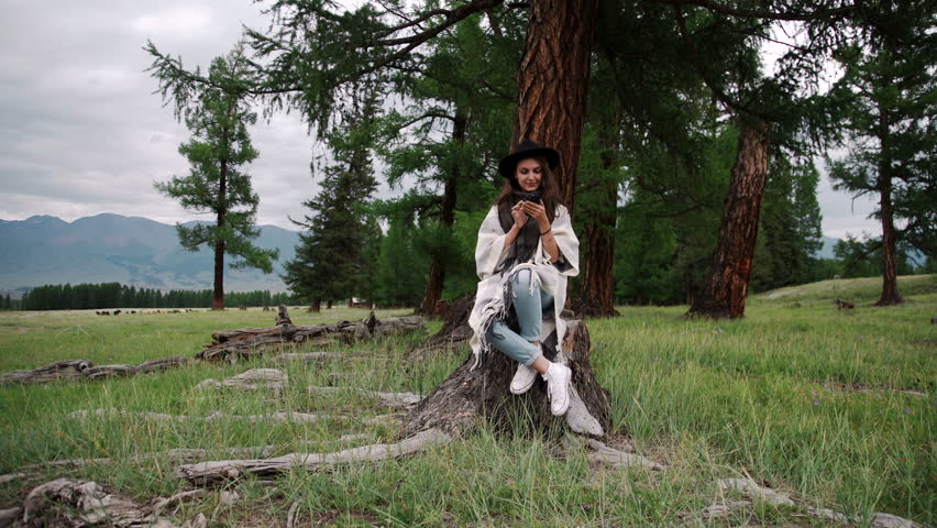 Smiling woman using mobile phone in park during the autumn