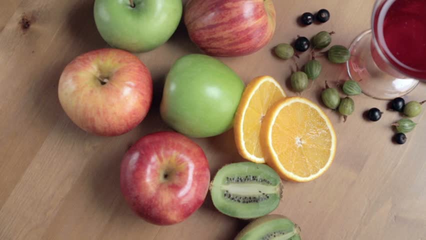 Fresh fruits on the table. Fruits still life. Beautiful arrangement of food on the table. Colorful fruits on the wooden table. Fruits mix. Apples, kiwis, orange, gooseberry.