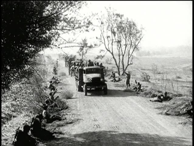 Roadside soldiers waving to passing military trucks