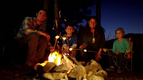 Portrait of happy Caucasian family toasting smores on holiday outdoor