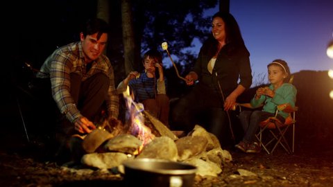 Happy American Caucasian family toasting smores in forest on vacation outdoor