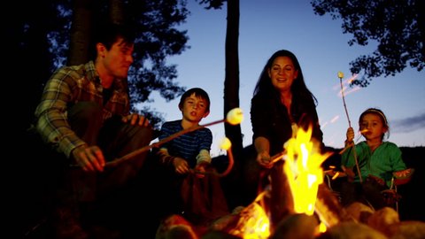 American Caucasian family enjoying camping and toasting smores outdoors