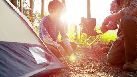 American Caucasian father and son erecting tent in forest on holiday outdoor