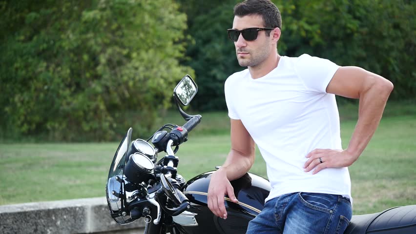 Close up of young handsome man on his vintage motorcycle. 