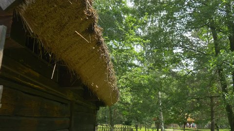 a Fragment of an Old House With Thatched Exterior.old Roof Made From Straw.fresh Green Grass Around Rural Huts