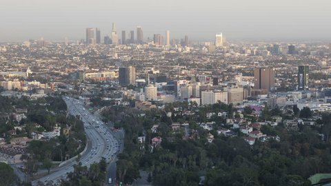 LOS ANGELES, USA - APR 15, 2015: 4k time lapse tilt up of sunset view of downtown Los Angeles from the Hollywood Hills with Interstate 101 in the foreground.