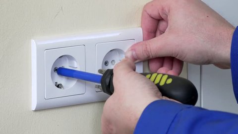 hands with screwdriver install outlet on wall