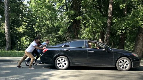 Men helping charming women to push car on road