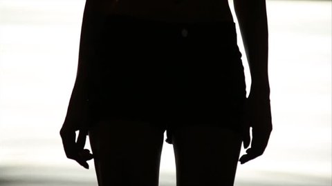 Silhouette of a sexy woman dancing go-go on white background of bright lights