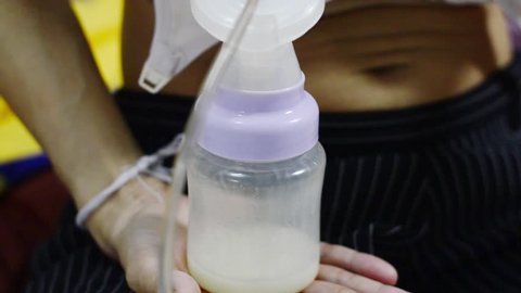 Mother pump breast milk with electric pump for her baby