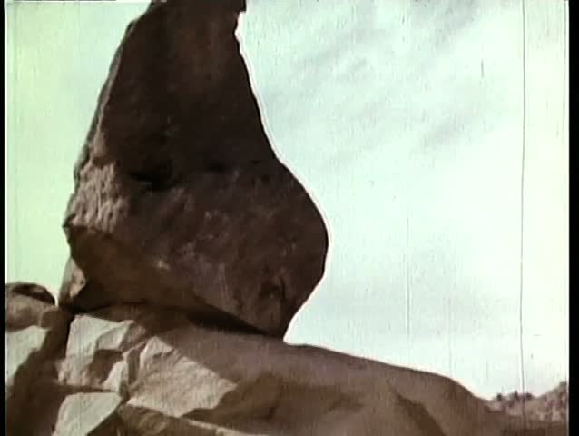 Pan down group of people standing on rock formation