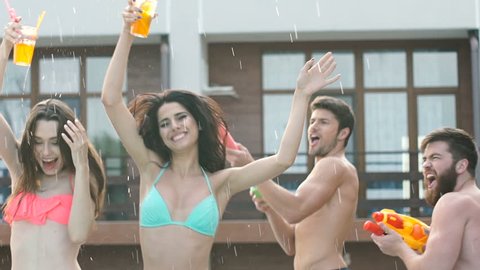 Happy young cheerful friends dancing and having fun at the pool