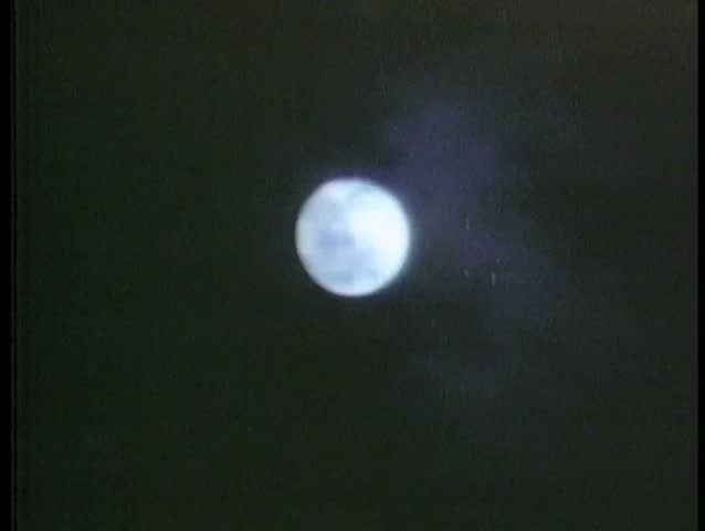 Clouds floating past full moon