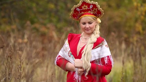 Beauty woman in traditional russian clothes is standing with kerchief.