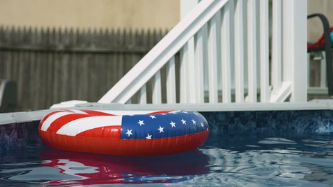 An american red white and blue styled float in a pool during summer