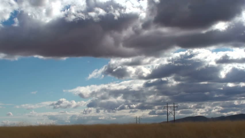 Time Lapse, Clouds swirl, dramatically, over grassland dotted with utility poles. 1920x1080