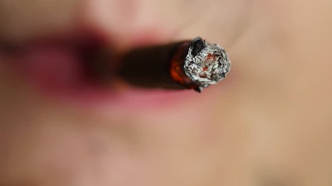 The man smokes a cigarette. It produces smoke. Tobacco. Close up