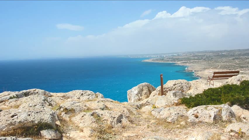 Vintage bench located on a top of rock with a view on Mediterranean Sea, Ayia Napa city and blue sky with clouds on Cyprus island.