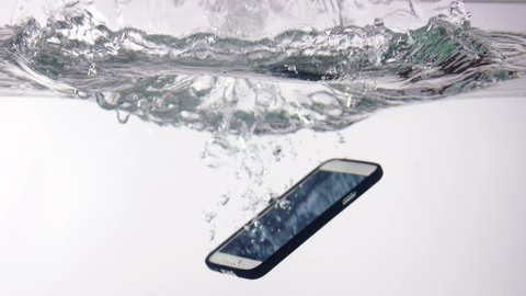 Smart phone with incoming call on display falling in water with splash on white background slow motion closeup