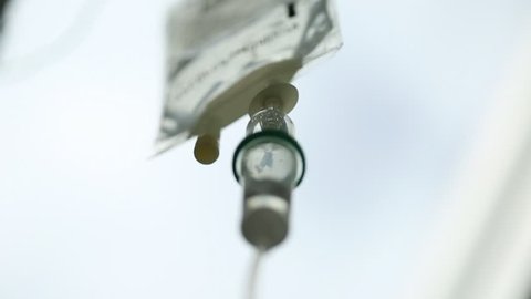 Extreme close up of intravenous iv drip slowly dripping away. Shot using a macro lens the depth of field is nice and shallow and every detail is very clear.