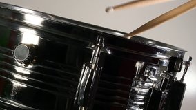 A closeup view of a drummer playing a snare drum with a white background.