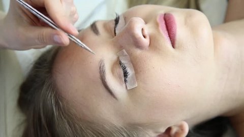 Beautiful young woman with eyelash extension. Woman eye with long eyelashes. Beautician eyelash extension for young woman in a beauty salon