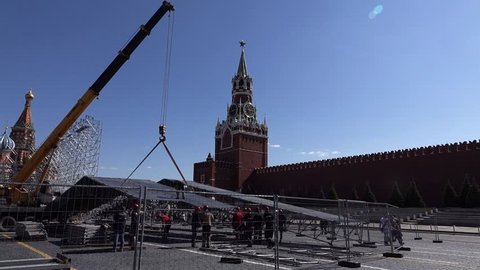 MOSCOW - MAY 13, 2016: Construction dismantling works at Red Square, unidentified personnel remove temporary scene roof after event. Mobile crane hold steel structure, temporary fence enclose area