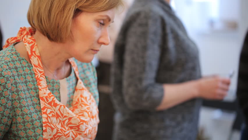 Blonde middle-aged woman lowers her head and crafts.