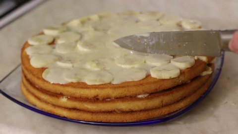 Female hands cut homemade cake with bananas, close up
