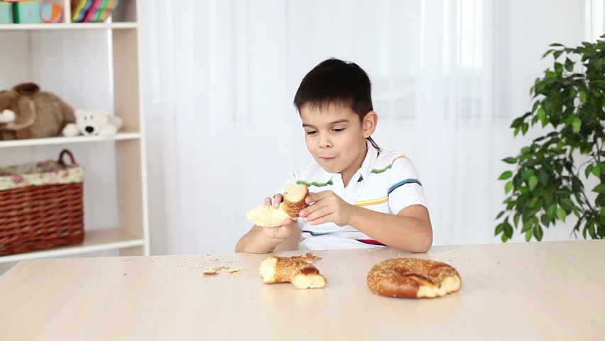 Boy eats bread sitting at the table