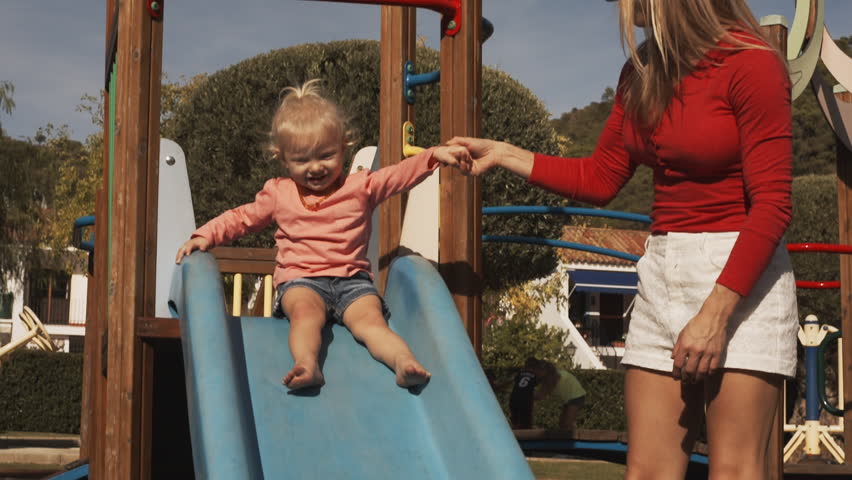 Mother and little girl on slide in playground