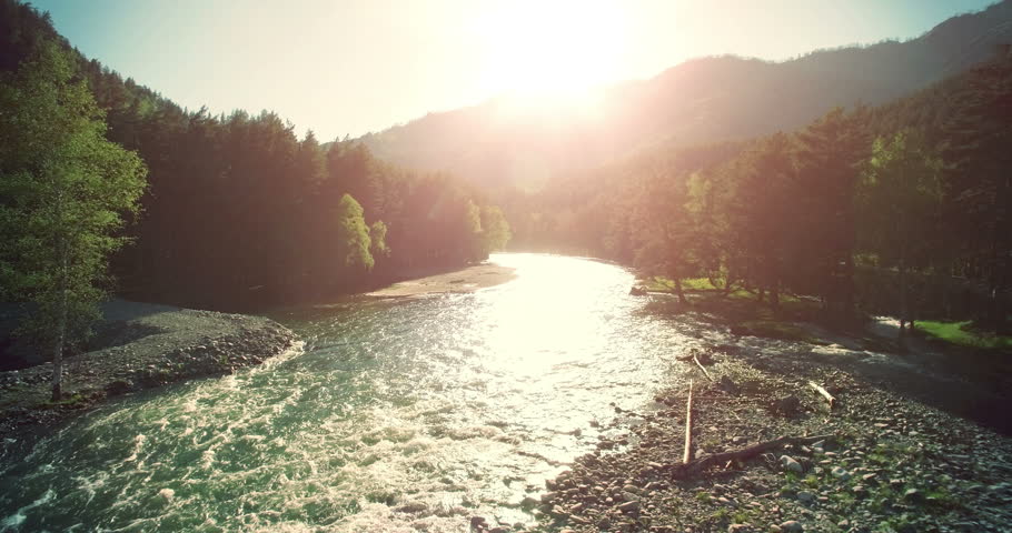 4k (UHD) aerial view. Low flight over fresh cold mountain river at sunny summer morning. Green trees and sun rays on horisont. Royalty-Free Stock Footage #18407554