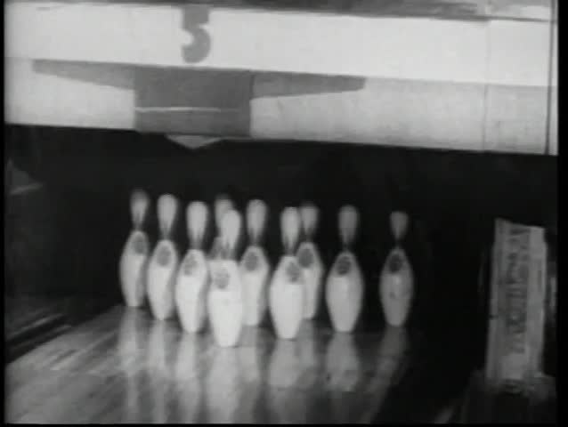 Bowling ball knocking down pins at bowling alley