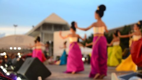 Blurred motion of Thai women dance dancing thai style for show people in traditional culture thai festival while raining at night time in Tha Nam Non Market in Nonthaburi, Thailand