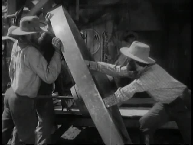 Men moving large wooden wheel