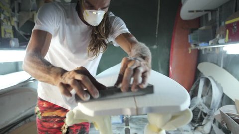 Surfboard shaping, Shaper sanding the nose of the surfboard with a sanding block. Concept of surfing craftsmanship, small business in America, craftsman at work.