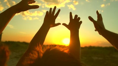 Happy family raising hands up, Father, mother and little son together enjoying nature outdoors. Hands silhouette over sunset sky. Vacation concept. Slow motion 240 fps. Full HD 1080p