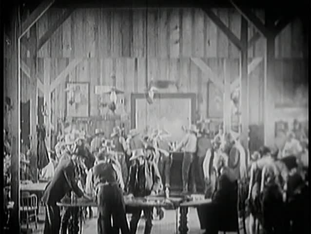 Wide shot of people dancing and gambling in saloon