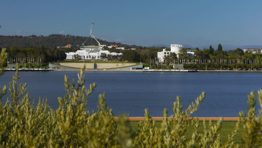 a dolly shot of the old and new parliament houses from across Lake Burley Griffin