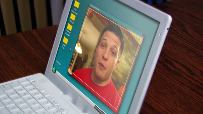 A young man video chats on a laptop.