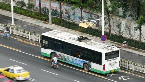 WUHAN, CHINA CIRCA JULY 2016, electric trolley bus stops in bus lane, overhead power contacts rise & hook up to cables under a cable guard hook up point, over head view, day, 