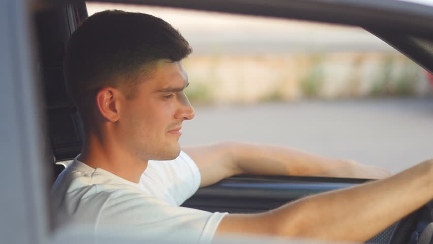portrait of a young man behing the wheel looks at camera, slow-motion