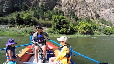 Confident American parent and children rafting on Colorado River on vacation