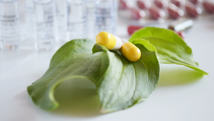 Pharmaceutical concept, two pills on the table in the green leaves. Pharmaceutical, medical background. Full HD 1080p stock footage video.