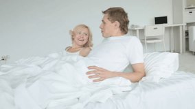 Dolly shot of couple lying in bed and talking