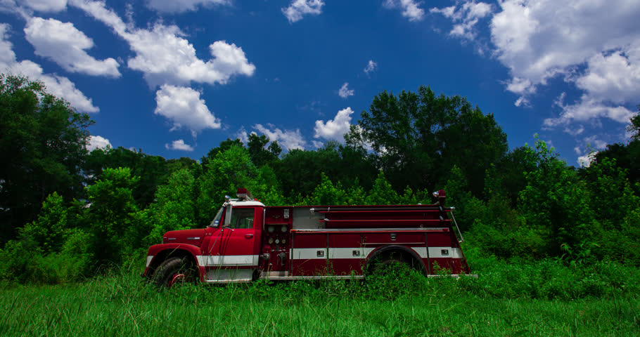 Old Model Red Firetruck in Green Field and Blue Sky