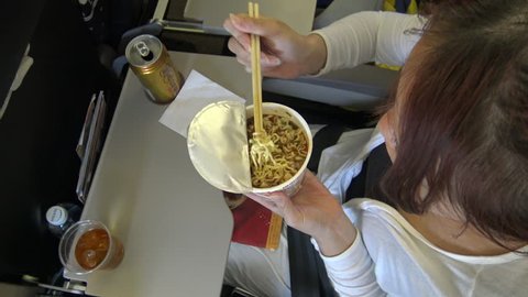 4k The asian woman passenger eating the instant noodles and drink tea in the interior of airplane during flight-Dan