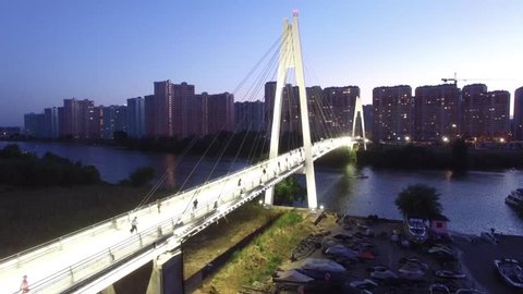 Pedestrian cable bridge in modern Moscow. Unique sunset evening aerial drone shot. Moscow river. People walk. 4K video.